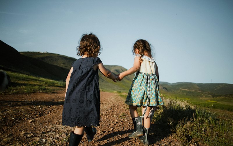 Two children walking outside hand in hand